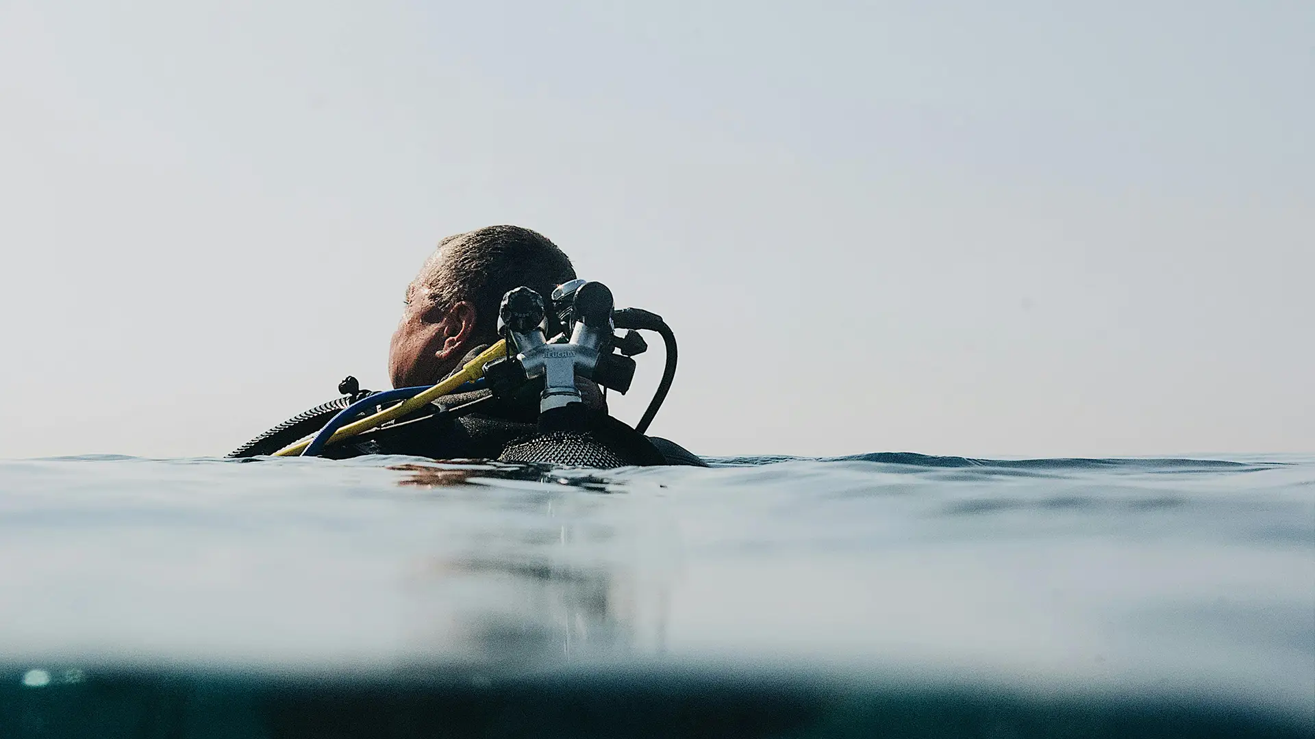Man's head as he emerges to the sea surface after scuba diving in Tolo