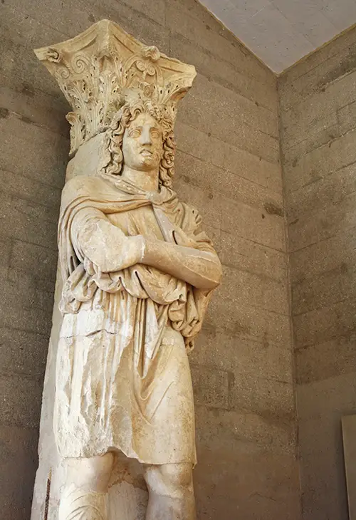 Marble statue of a man infront of a Corinthian style column, the Frygian captive